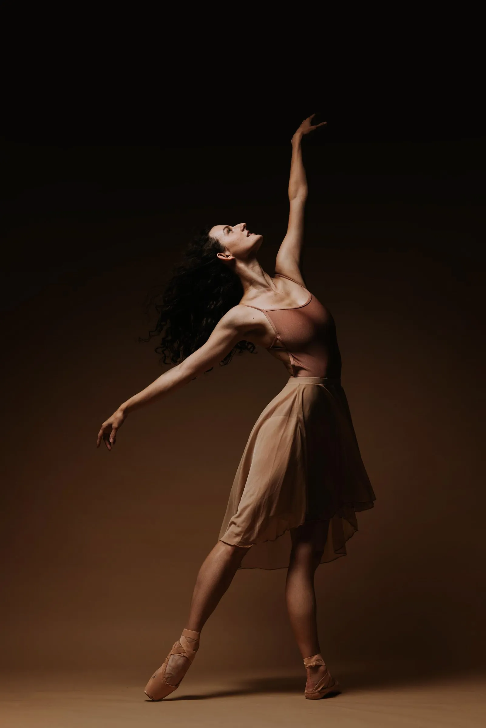 Grace Manuel reaching upward in a pale dress