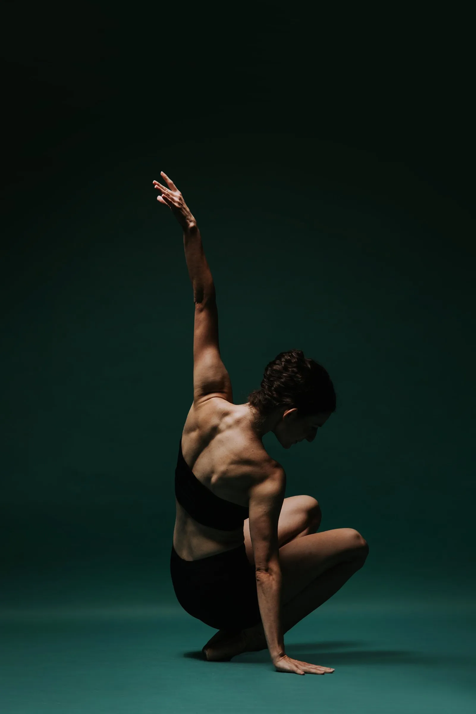 Grace Manuel crouched low with one arm extended upward