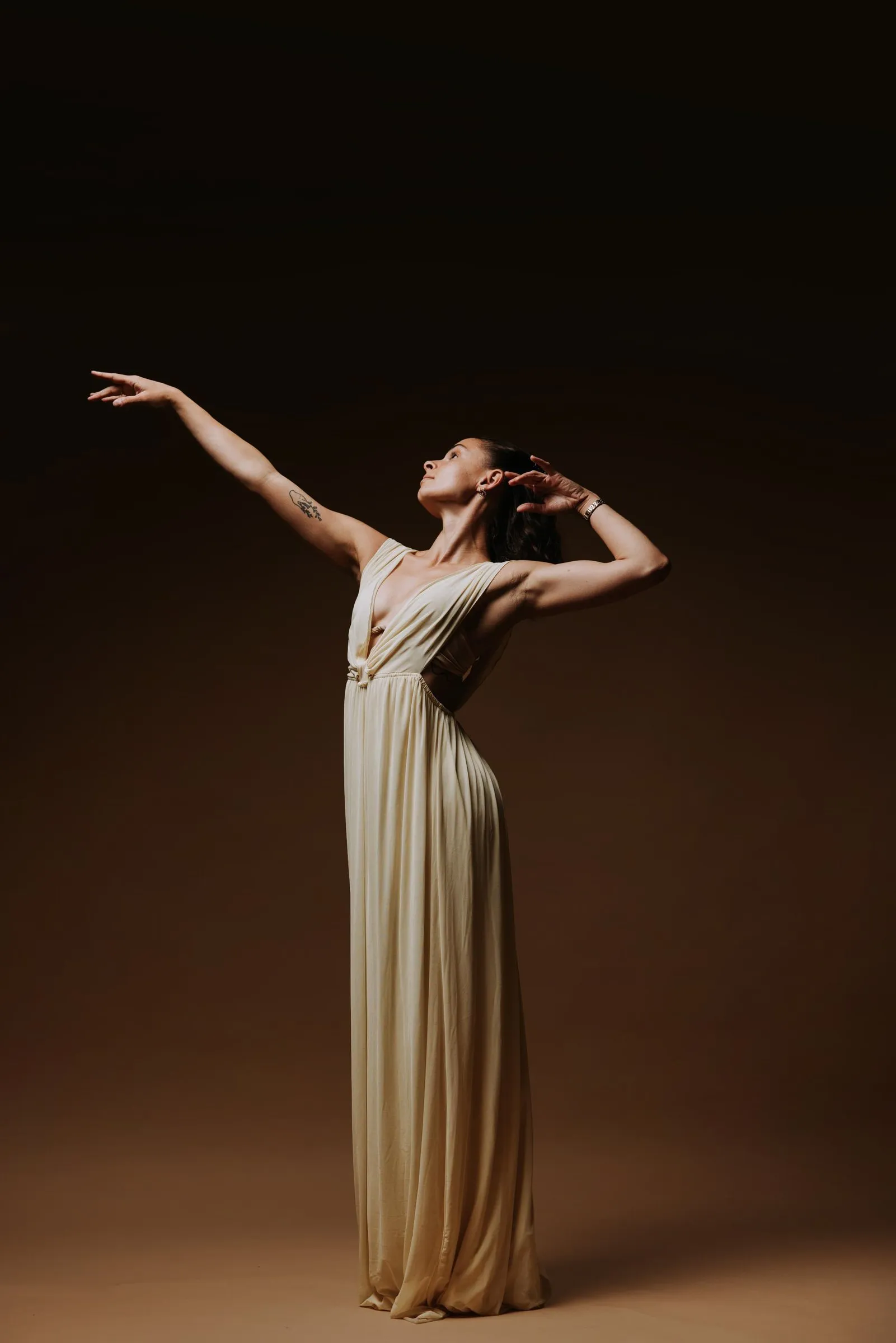 Paige Russell in a cream gown, arms lifted