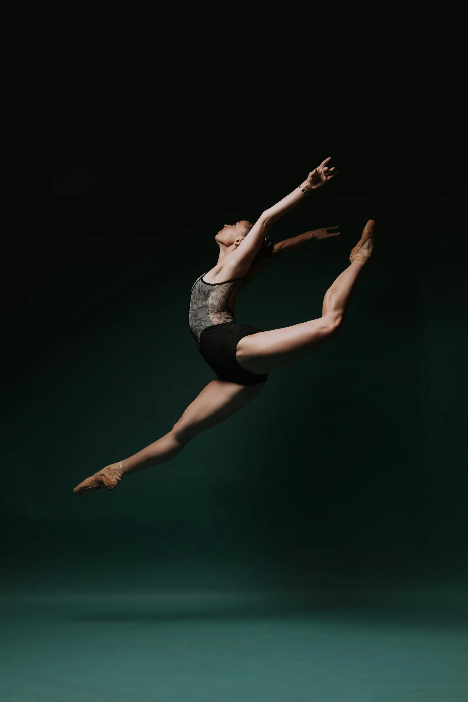 Paige Russell in a split leap against dark teal