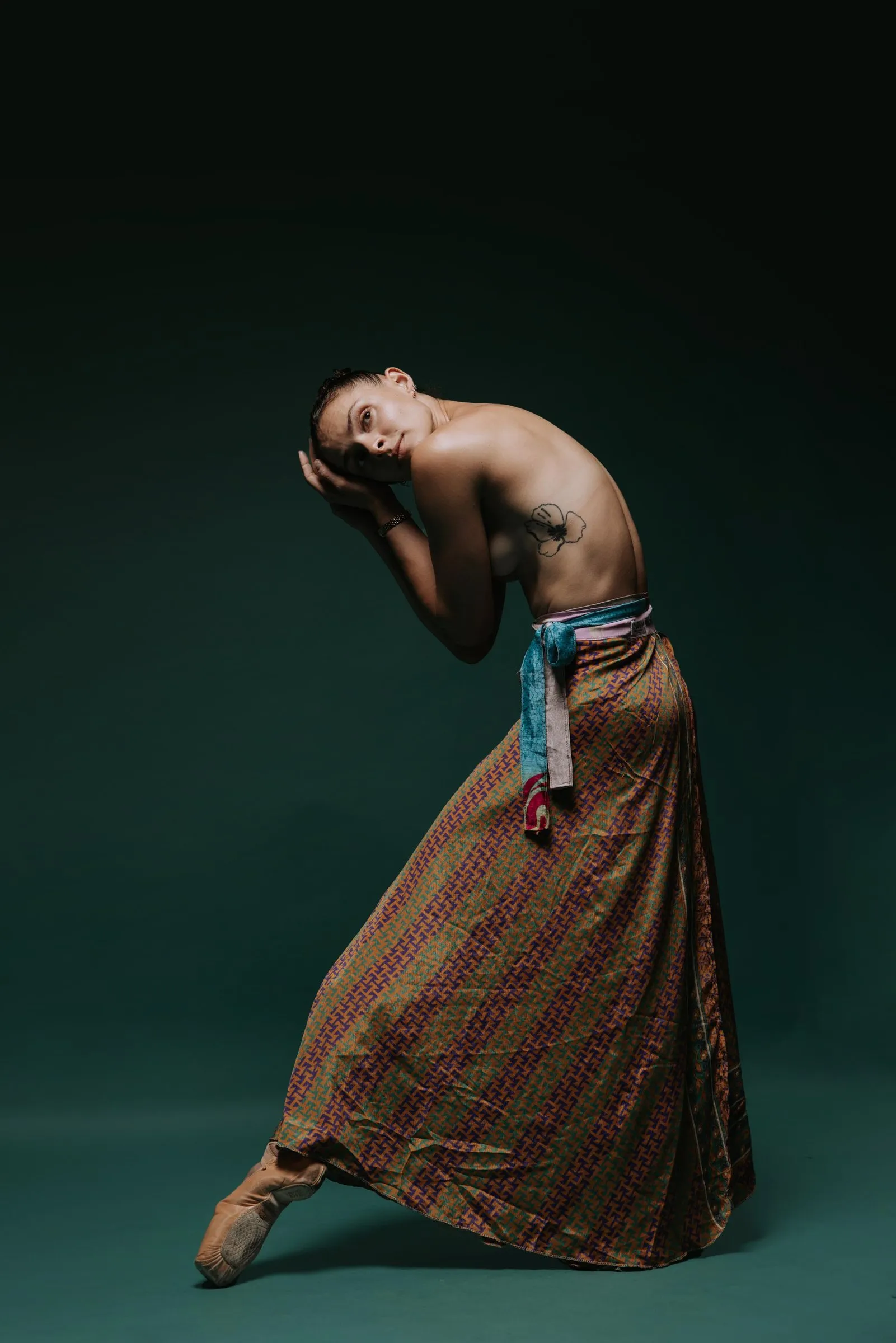 Paige Russell bowing forward in a long patterned skirt